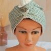 Serviette à cheveux turban avec motif géométrique d'hexagones et éventails verts, doublure éponge blanche et bouton transparent discret.