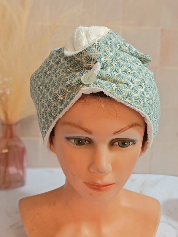 Serviette à cheveux turban avec motif géométrique d'hexagones et éventails verts, doublure éponge blanche et bouton transparent discret.