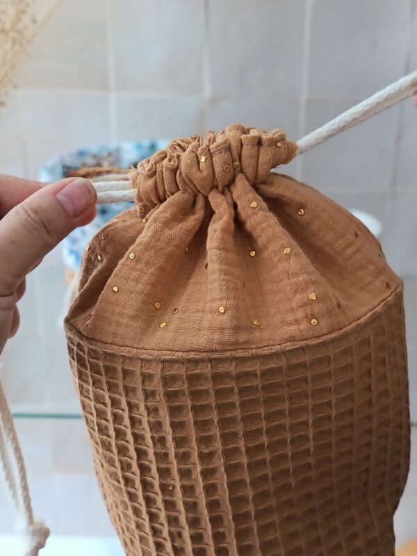 Détail de la matière double gaze de coton ocre avec petits points dorés brillants et système de fermeture par cordon.