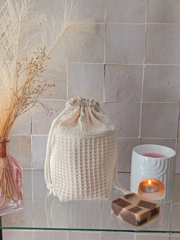 Panier de rangement en tissu crème composé d'une base en nid d'abeille et d'un haut en double gaze de coton parsemé de pois dorés.