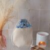 Panier de rangement en tissu nid d'abeille crème avec fermeture par cordon et doublure à motifs floraux bleus, style bohème.