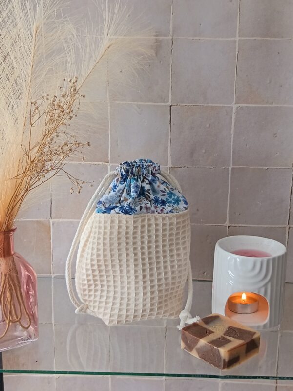 Panier de rangement en tissu nid d'abeille crème avec fermeture par cordon et doublure à motifs floraux bleus, style bohème.