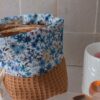 Détail du revers d'un panier de rangement montrant une doublure en coton aux motifs fleurs bleues et feuillage.