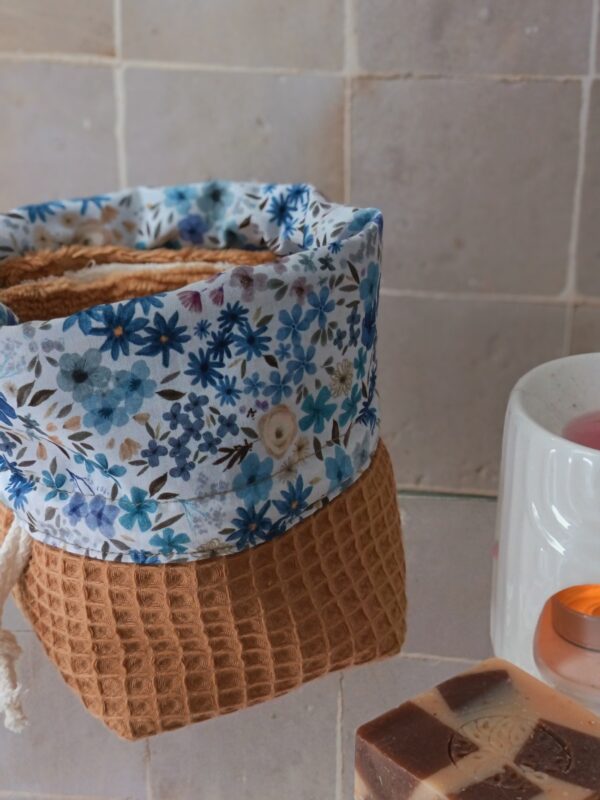 Détail du revers d'un panier de rangement montrant une doublure en coton aux motifs fleurs bleues et feuillage.