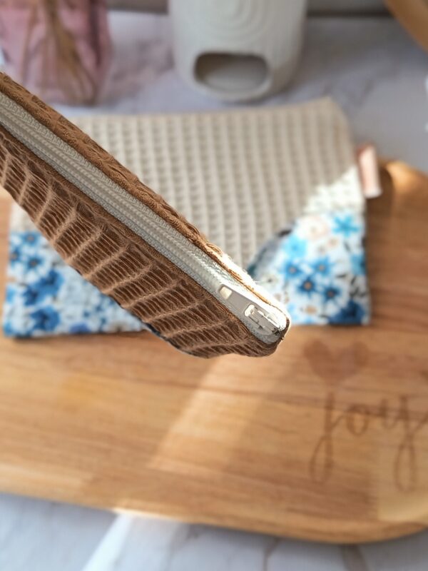 Gros plan sur la fermeture éclair blanche et les finitions de qualité d'une pochette faite main.