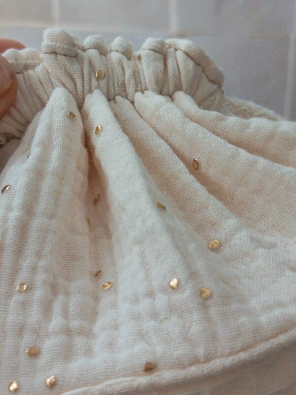 Main tenant les cordons de serrage blancs d'un panier de rangement en tissu pour montrer la fermeture coulissante.