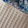 Gros plan sur les textures : tissu nid d'abeille écru et coton imprimé floral bleu de la collection Douceur Ocre Bleutée.