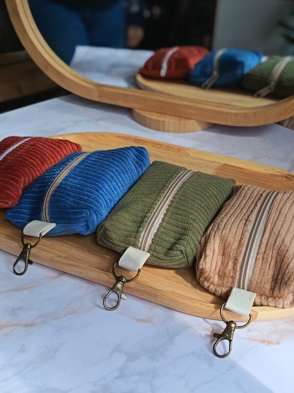 Vue frontale de quatre étuis en velours côtelé de la collection Malili_fée sur un plateau en bois, se reflétant dans un miroir en arrière-plan.