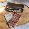 Essuie-lunettes artisanal Malili_fée en coton vichy terracotta et blanc, posé à côté de sa face minky douce sur un plateau en bois.