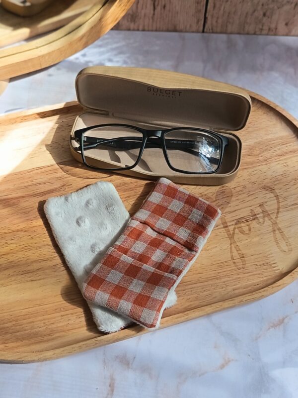 Essuie-lunettes artisanal Malili_fée en coton vichy terracotta et blanc, posé à côté de sa face minky douce sur un plateau en bois.