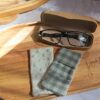 Essuie-lunettes tissu double gaze vichy vert pastel, posé sur un plateau en bois à côté de sa face minky blanche réversible.
