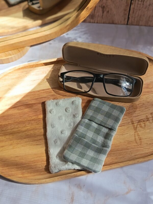 Essuie-lunettes tissu double gaze vichy vert pastel, posé sur un plateau en bois à côté de sa face minky blanche réversible.