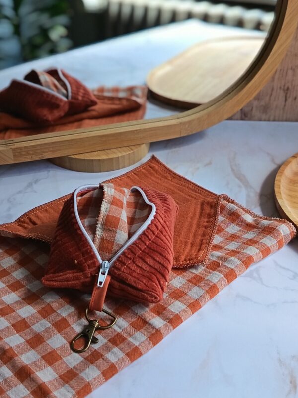 Kit mouchoirs zéro déchet coloris Terracotta : un étui nomade en velours côtelé terracotta avec mousqueton et ses deux mouchoirs artisanaux en double gaze vichy dépliés.
