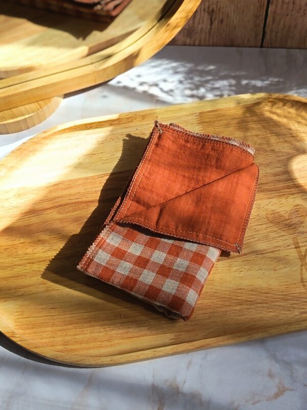 Mouchoir tissu double gaze artisanal plié, motif vichy terracotta et blanc, posé sur un plateau en bois.