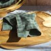 Mouchoir tissu double gaze artisanal Malili_fée, coloris vichy vert pastel, déplié sur un plateau en bois.
