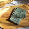 Mouchoir tissu double gaze plié, motif vichy vert pastel, un accessoire zéro déchet élégant sur un plateau en bois.