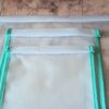 Gros plan sur les finitions et les coutures régulières de deux sacs de congélation écologiques lavables. On observe le biais en tissu vert menthe parfaitement posé sur les bords du film EVA étanche.