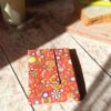 Emballage à sandwich réutilisable lavable avec son motif de fleurs japonaises rouge, jaune et ocre. Présentation du produit plié au format compact pour la miniature de variation.