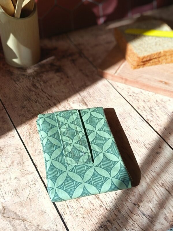 Emballage à sandwich réutilisable et imperméable décliné en coton enduit vert sauge avec un motif géométrique de rosaces et de lignes fines.