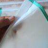 Une main entrouvre le système de fermeture d'un sac de congélation lavable. La mise au point met en valeur la bande de scratch blanc auto-agrippant solidement fixée sur le bord supérieur en film EVA.