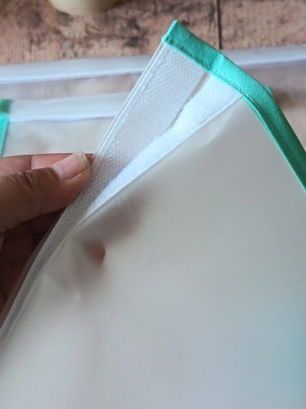 Une main entrouvre le système de fermeture d'un sac de congélation lavable. La mise au point met en valeur la bande de scratch blanc auto-agrippant solidement fixée sur le bord supérieur en film EVA.