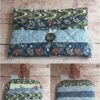 Housse de livre de poche en tissu Modèle 1 gris et doré à motifs vagues, avec livre glissé dans la poche intérieure.