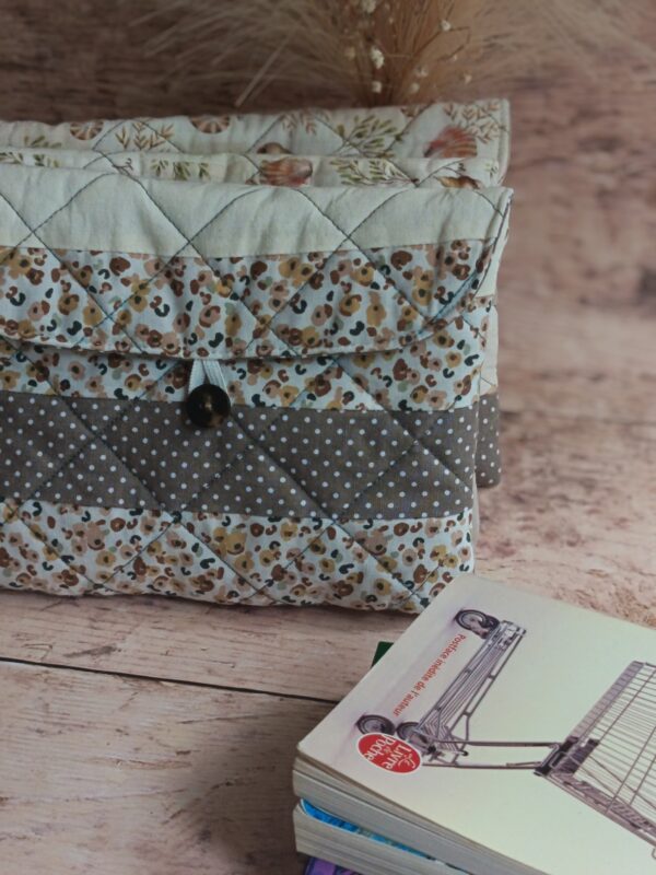 Pochette à livre de poche écoresponsable matelassée à motif léopard et pois, présentée avec un roman de poche.