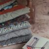 Pile de plusieurs pochettes à livre de poche écoresponsables matelassées aux tons neutres, terracotta et beige.