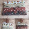 Pochette à livre de poche écoresponsable Modèle 2 matelassée terracotta et beige, à motifs visages abstraits et plumes.