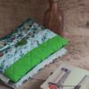Pochette à livre de poche faite main matelassée aux motifs végétaux vert pomme et vert canard, posée près de livres.