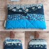 Pochette à livre de poche Modèle 4 au design épuré, combinant un tissu matelassé bleu canard et un motif de fleurs blanches délicates.