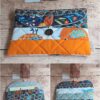 Pochette à livre de poche originale Modèle 2 aux motifs d'oiseaux et papillons orange, fermée par un bouton marron.