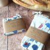 Sacs à pain réutilisables en coton pliés sous leur bandeau de présentation écologique en papier kraft.