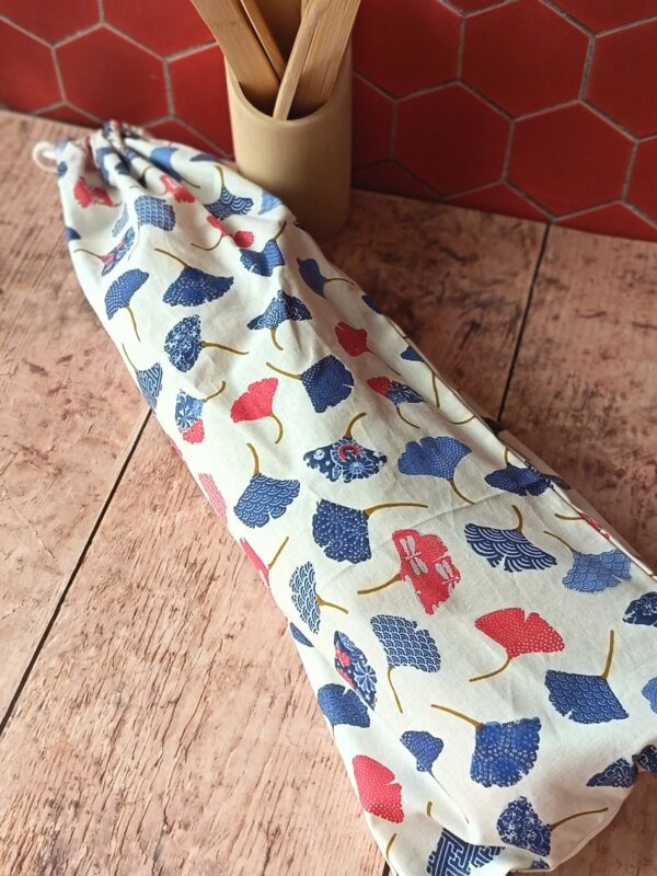 ac à baguette réutilisable en coton motif feuilles de ginkgo japonais bleu et corail, posé sur une table en bois.