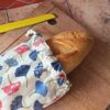 Baguette de pain artisanale dépassant d'un sac à baguette nomade en coton motif ginkgo fermé par un cordon.