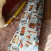 Sac à baguette réutilisable en coton motif boulangerie rétro avec baguettes et 2CV, posé sur une planche en bois.