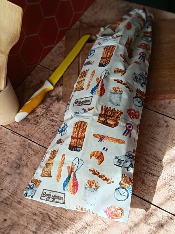 Sac à baguette réutilisable en coton motif boulangerie rétro avec baguettes et 2CV, posé sur une planche en bois.