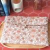 Pochette grand livre tissu matelassée motif Fleur Pastel avec bouton en bois posée sur plateau