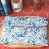 Pochette grand livre tissu matelassée motif Romane aux fleurs bleues et violettes sur plateau en bois