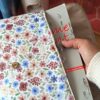 Main glissant un pavé volumineux dans la pochette grand livre tissu Rozenn Prune matelassée