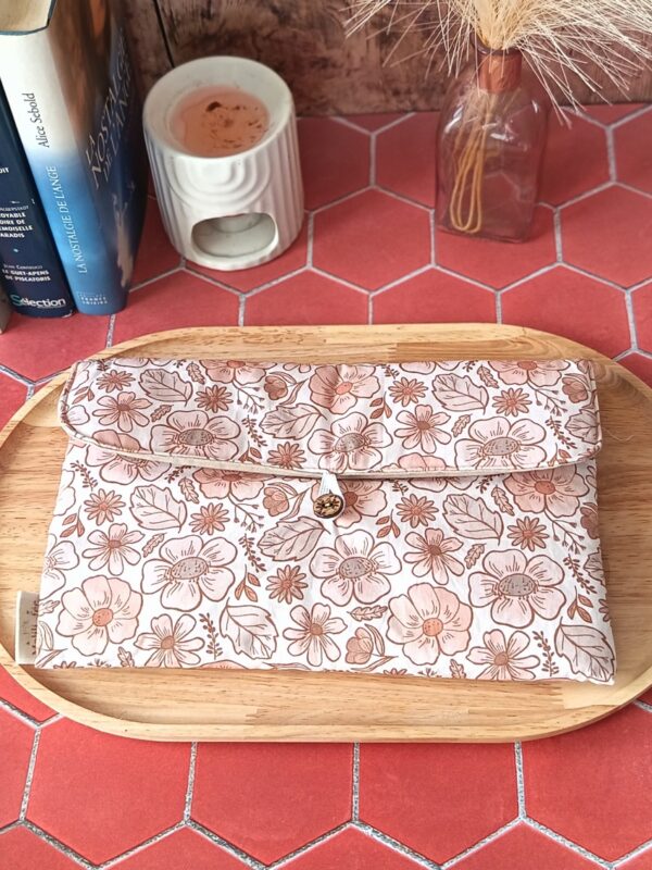 Pochette livre broche tissu matelassée motif Fleur Pastel avec bouton en bois posée sur un plateau