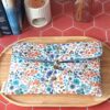 Pochette livre broche tissu matelassée motif Hortense Bleu fermée par une bride élastique et bouton