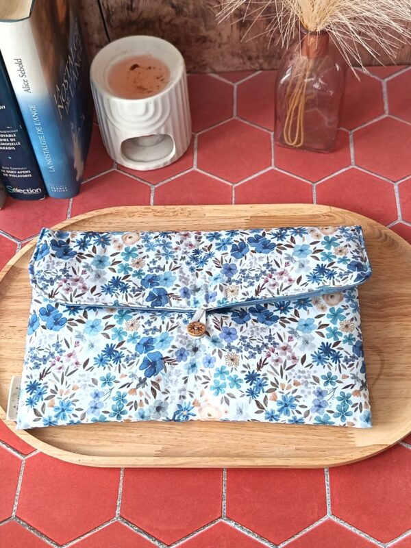 Pochette livre broche tissu matelassée motif Romane aux fleurs bleues et violettes sur plateau en bois