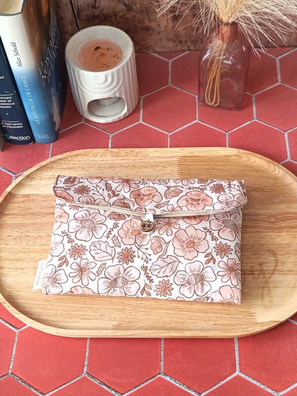 Alt : Pochette livre de poche tissu matelassée motif Fleur Pastel avec bouton en bois posée sur un plateau