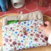 Pochette livre de poche tissu Rozenn Prune matelassée tenue en main avec un roman à l'intérieur