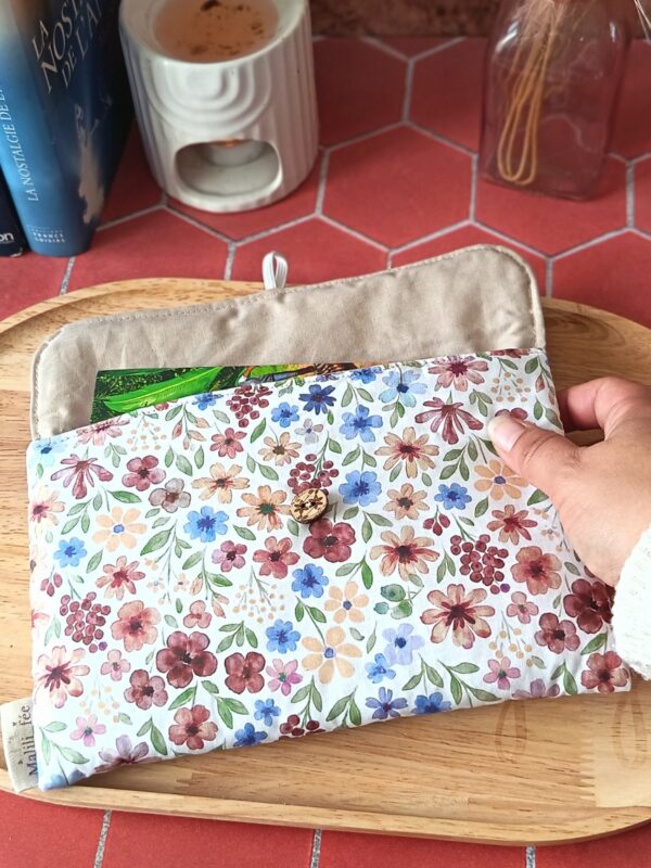 Pochette livre de poche tissu Rozenn Prune matelassée tenue en main avec un roman à l'intérieur